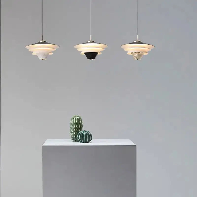 Three tiered modern pendant lights in cream wind milk glass hanging in kitchen dining area