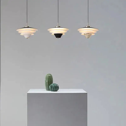 Three tiered modern pendant lights in cream wind milk glass hanging in kitchen dining area