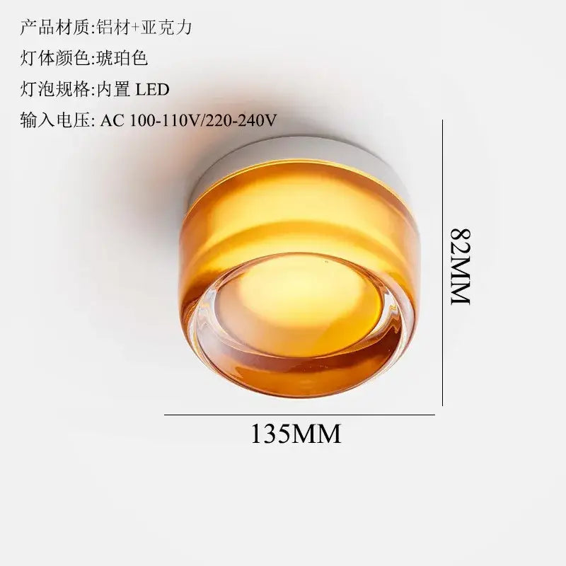 A sleek amber dimple potato chip wall lamp with cylindrical acrylic body and aluminum top featuring integrated led bulb