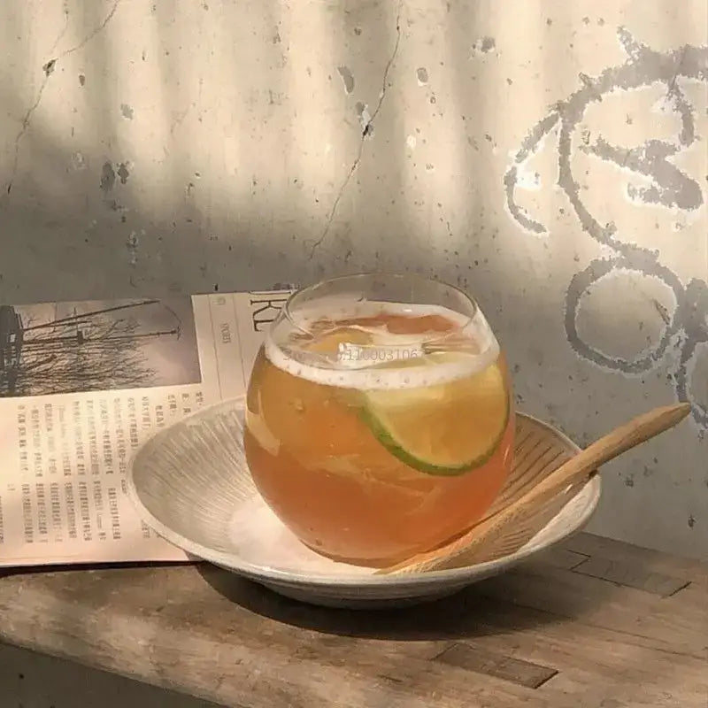 Modern transparent glass coffee mug filled with orange beverage garnished with lime slice and frothy foam for kitchen use