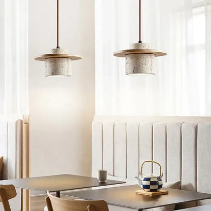 Two modern travertine and walnut pendant lights with textured concrete bodies and cord pendant led bulbs for kitchens