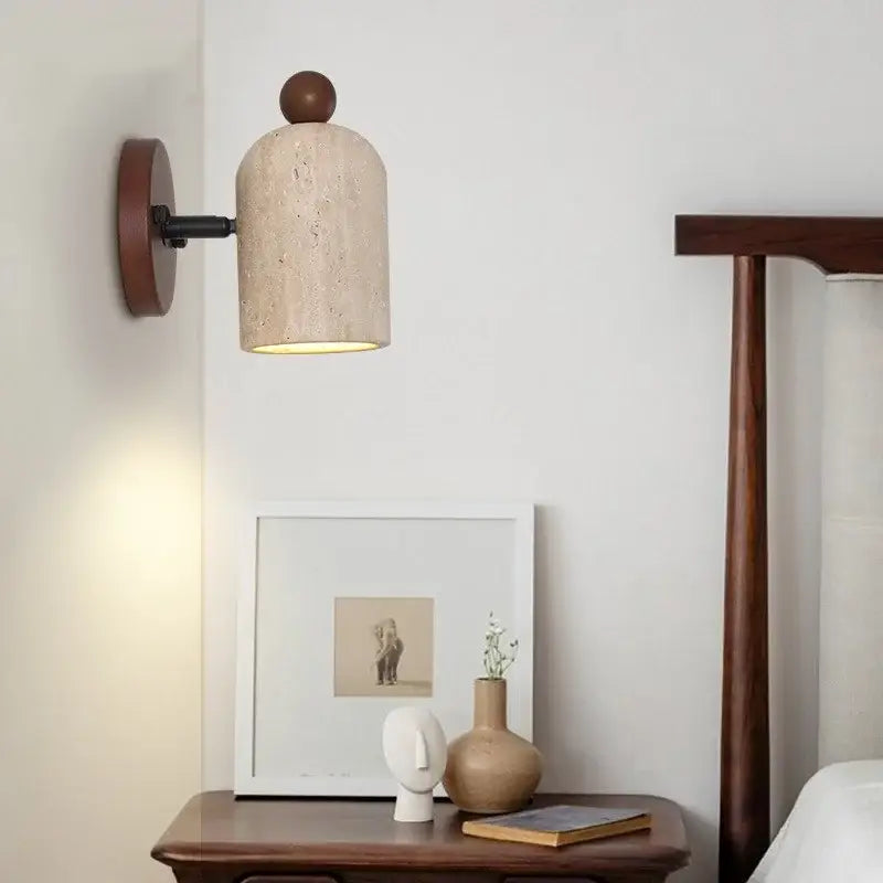 Beige travertine textured wall light fixture with dark wood circular backplate and spherical top accent for bedroom use