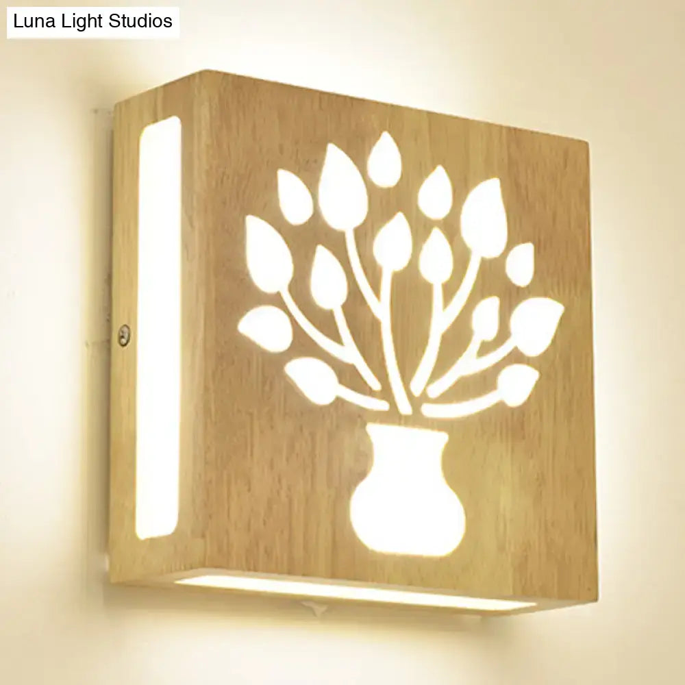 A square light-colored wood grain wall light with a direct wired electric design and intricate tree pattern cut-out