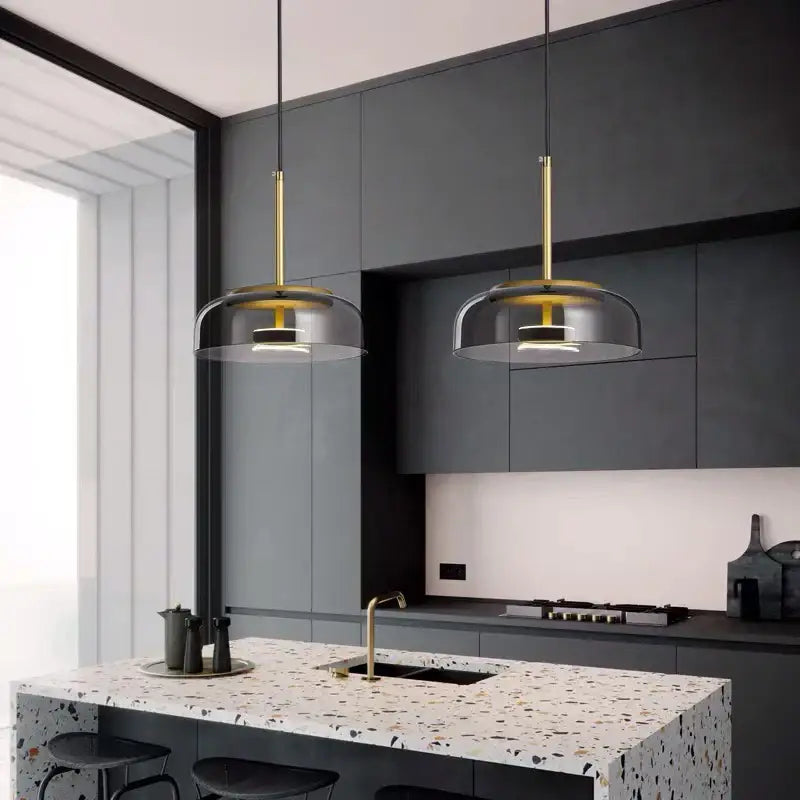 Two modern pendant lights with gold-finished rods and translucent dome glass shades for dining room use