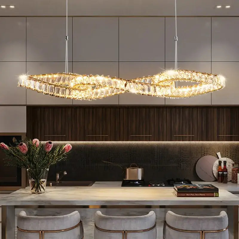 Modern twisted gold metal crystal pendant light with infinity shape and sparkling accents above kitchen island