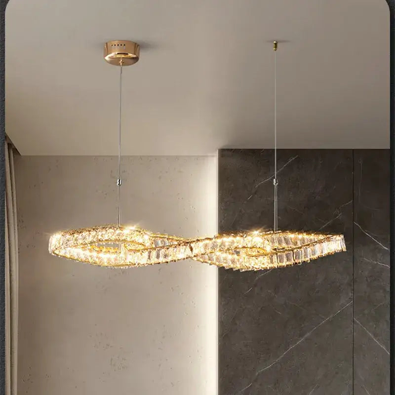 Modern infinity-shaped pendant light with decorbites gold metal frame and sparkling gold metal crystal accents for dining room