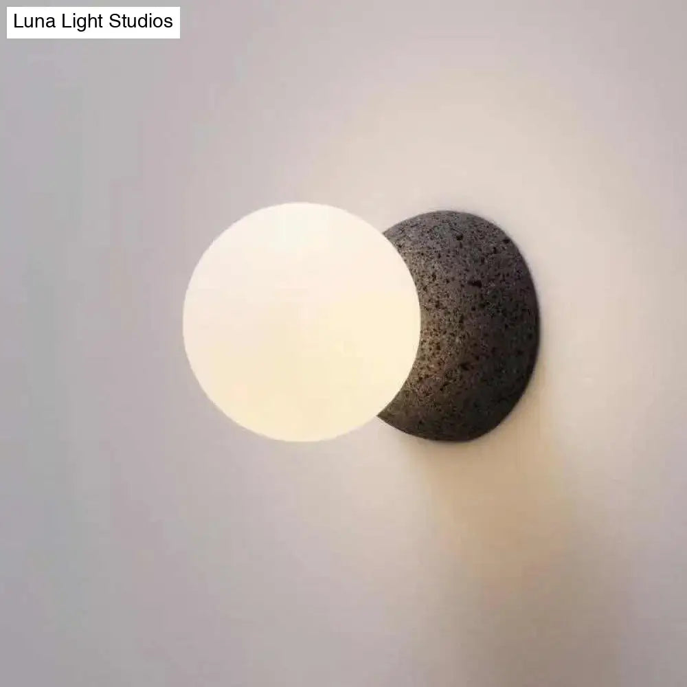 Minimalist wall lamp with white glass spherical globe on dark volcanic stone base for living room inch fixture