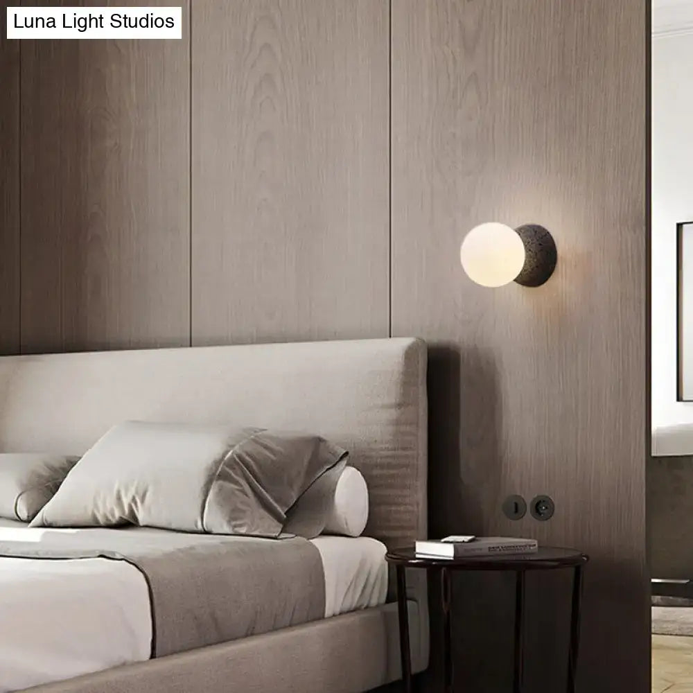 Modern wall lamp with matte black textured bulb base and white glass frosted globe for living room lighting