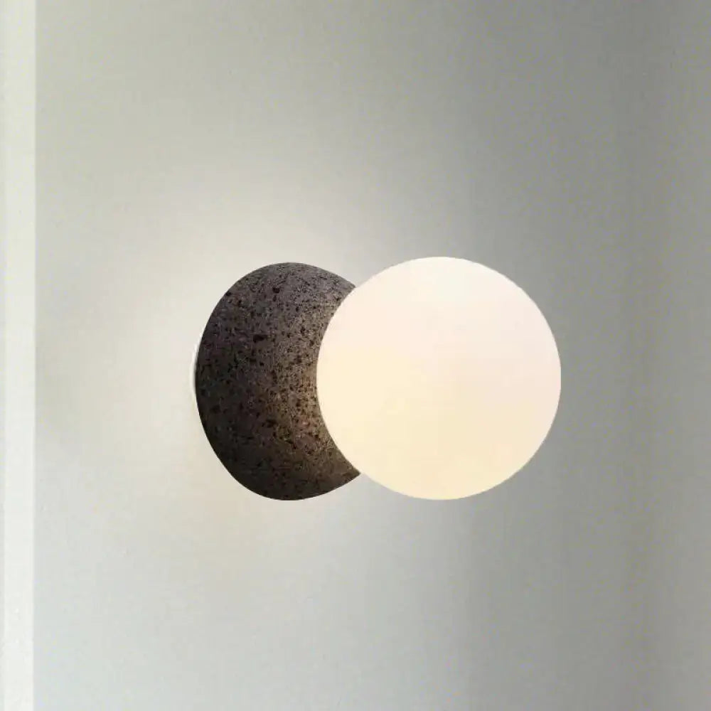Modern wall lamp with dark volcanic stone bulb base and smooth white glass shade for stylish living room decor