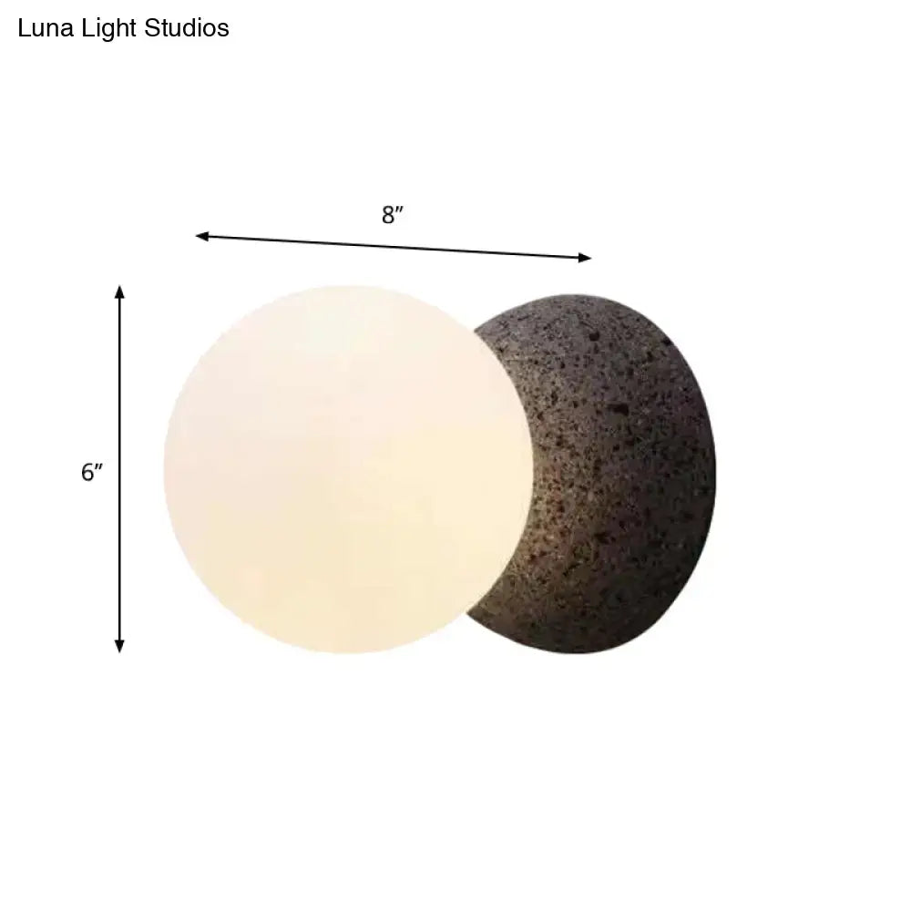 Modern volcanic stone and white glass wall lamp with dual-toned spherical design and integrated bulb base for living room