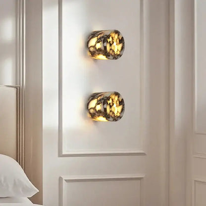 Modern wabi sabi black and cream resin led wall lamp with amber marbled glass emits soft golden light on white wall