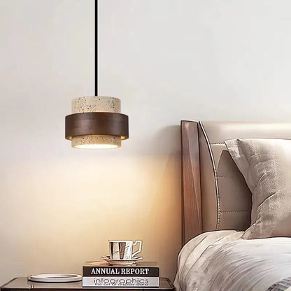Modern wabi sabi tiered stone pendant light with textured beige concrete body and dark bronze bands on black cord pendant