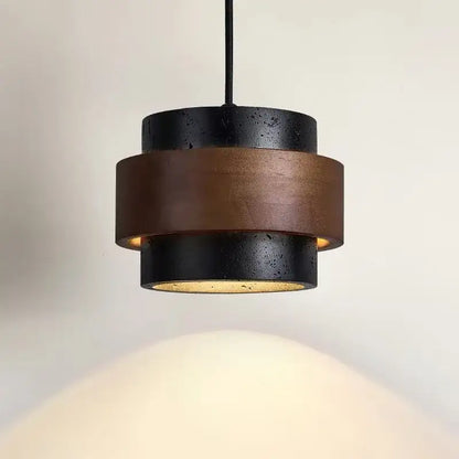 Modern wabi sabi tiered stone pendant light with black and bronze layers and textured concrete finish for dining room