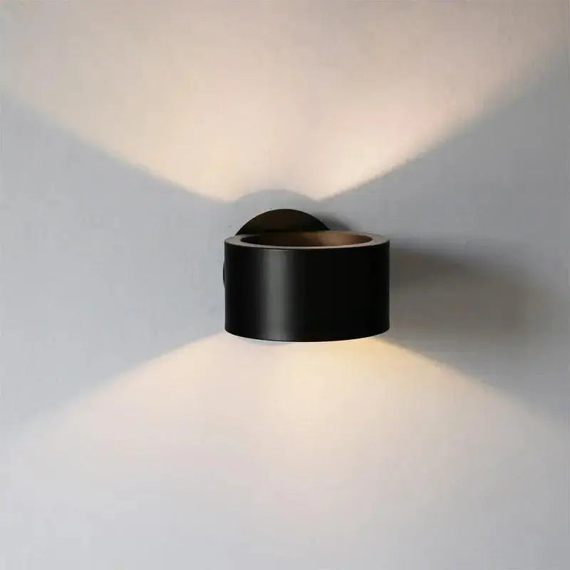 Modern wall lamp black gold with a sleek cylindrical design casting warm light in two distinct beams