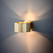 Gold-toned modern wall lamp with sleek segmented barrel design for stylish indoor lighting