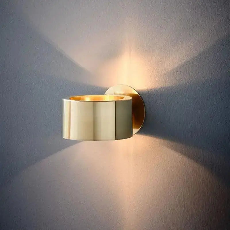 Gold-toned modern wall lamp with sleek segmented barrel design for stylish indoor lighting