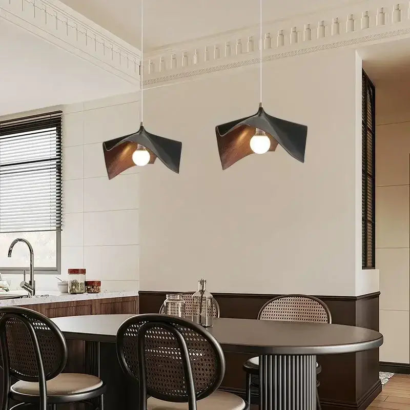 Modern wave black and bronze chandelier pendant light with sculptural wing design hanging above dining table