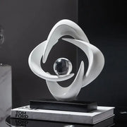 Modern white abstract resin sculpture figurine with flowing curves encircling glass sphere on black base decorbites abstract resin decor