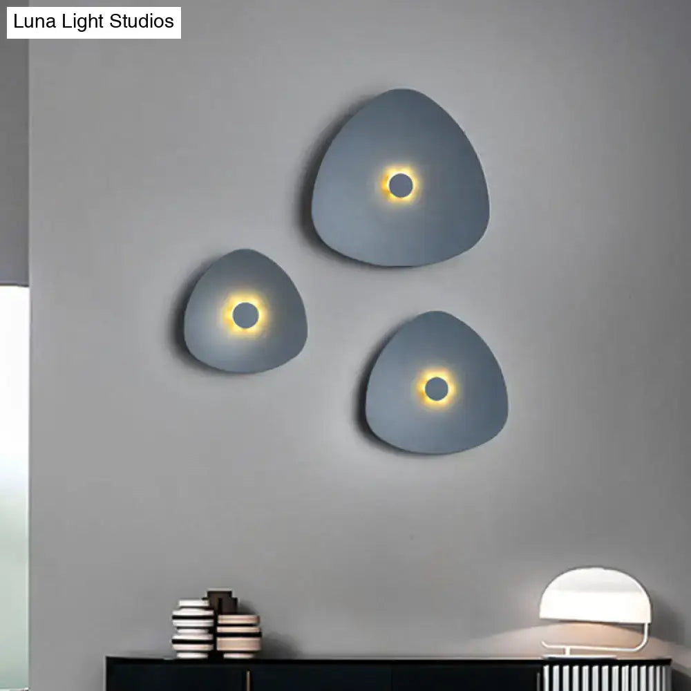 Set of three modern gray flaky sconce light fixtures with warm circular centers for bedroom wall lighting
