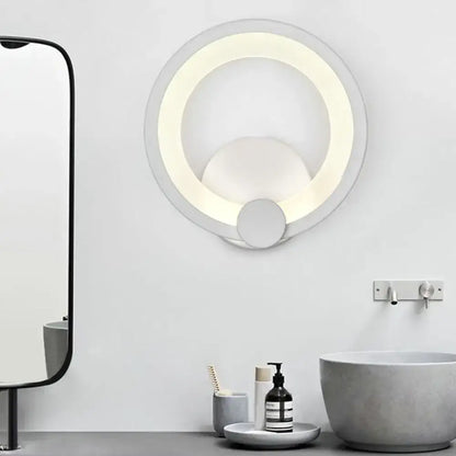 Modern white acrylic sconce light with layered concentric rings emitting soft warm light for bedroom walls