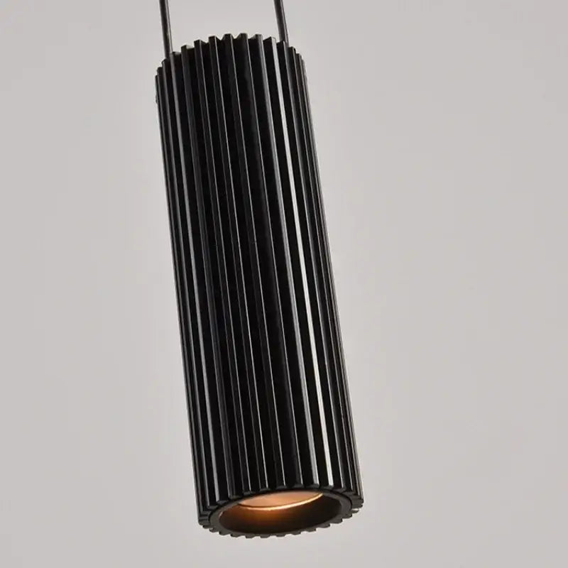 Modern white and black circular pendant light with black cylindrical vertical ridges and warm-toned interior decorbites circular pendant