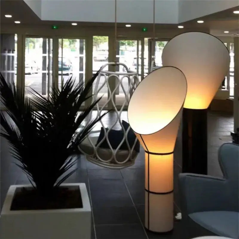 Modern white and black horn floor lamp with a warm glowing cylindrical shade and sleek black metal frame for decorbites horn floor decor