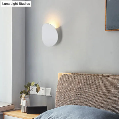 Modern style wall sconce in white and black with sleek oval design emitting warm led light for bedroom use