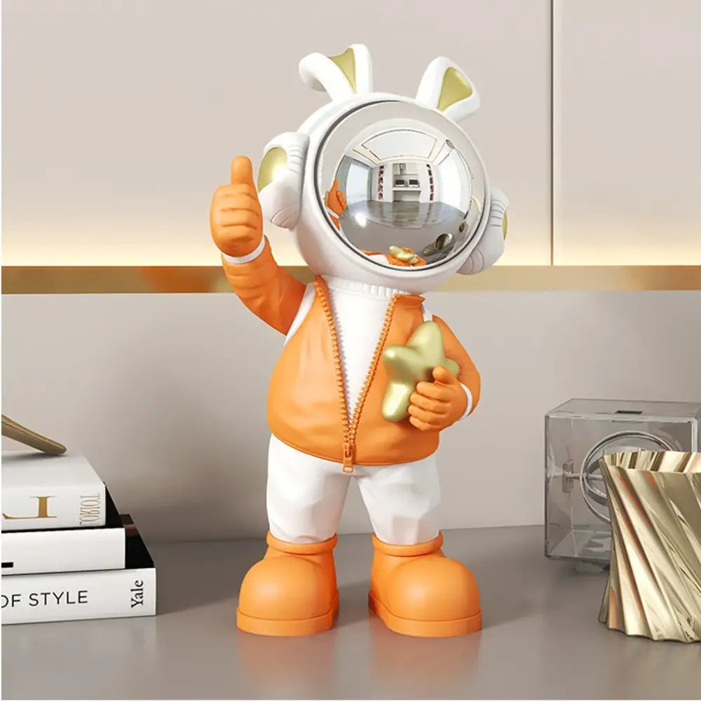 Modern white and blue astronaut resin sculpture featuring an orange astronaut resin with bunny ears holding a golden star