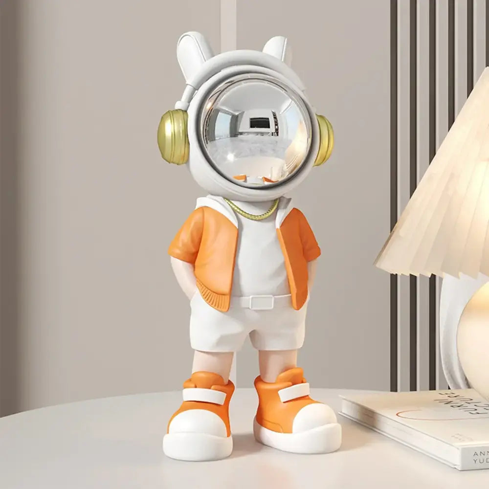 Modern white and blue astronaut resin sculpture featuring a cute astronaut with gold headphones and orange attire for living room decor