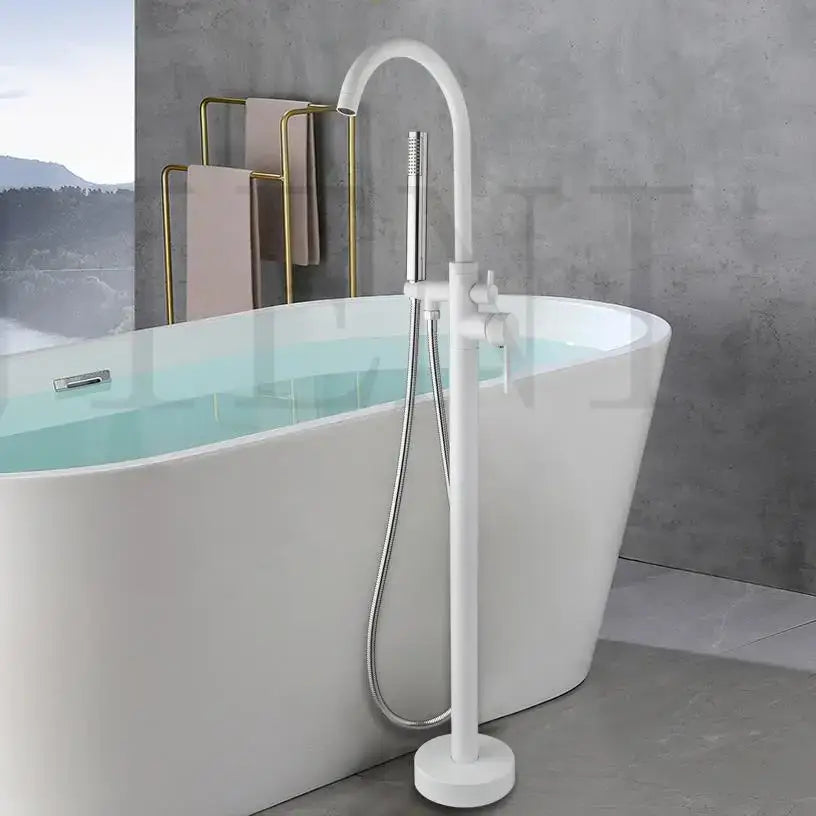 Modern white freestanding bathtub with a chrome curved faucet in a sleek bathroom floor mount faucet set