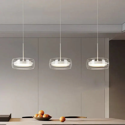 Three modern pendant lights with clear glass shades and white rings hang above a dining table for remote dimming use