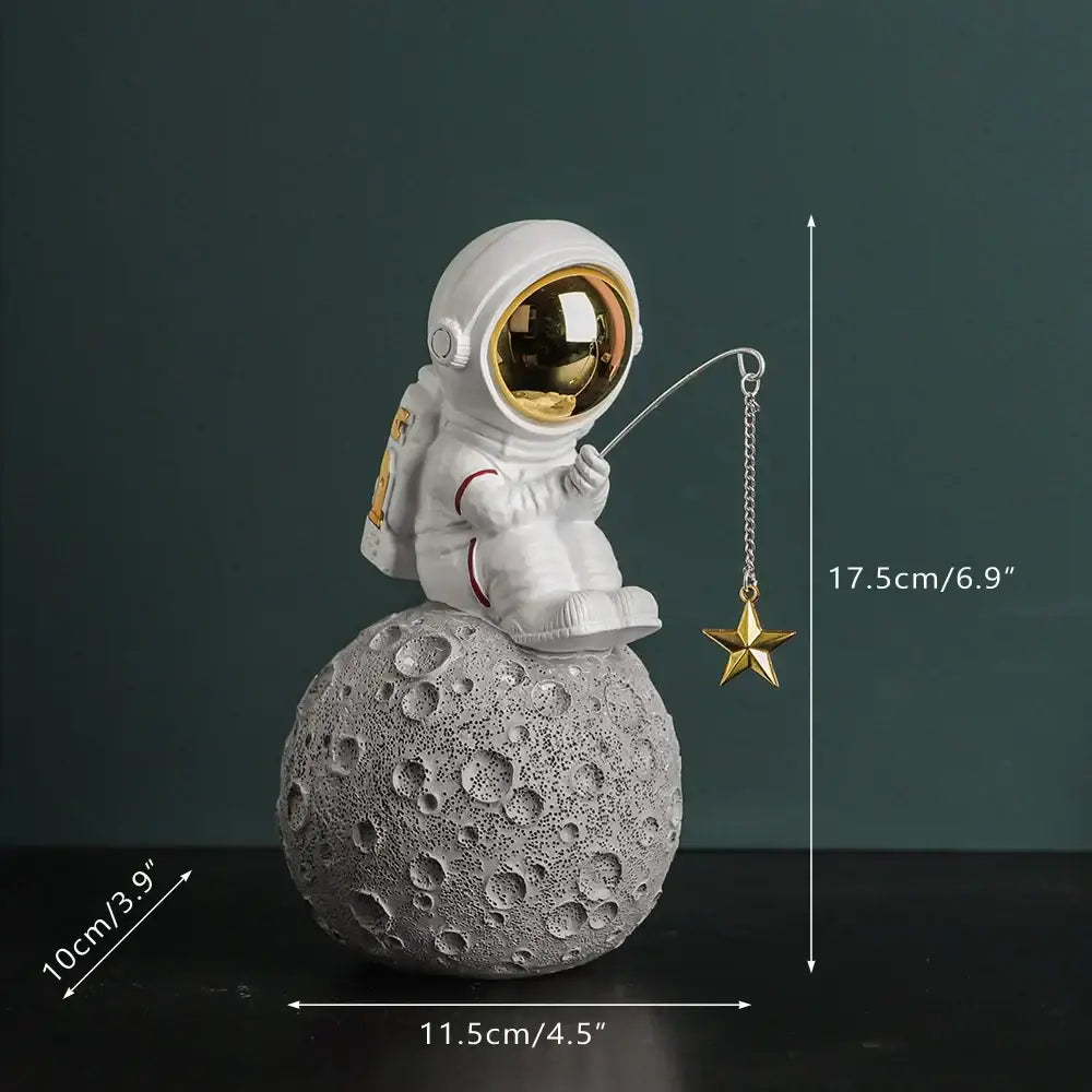 Modern white and electroplated golden astronaut figurines with gold visor holding star on textured gray moon surface decor