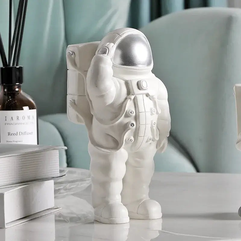 Modern white and gold astronaut phone holder with metallic silver helmet standing on table decorbites astronaut phone decor