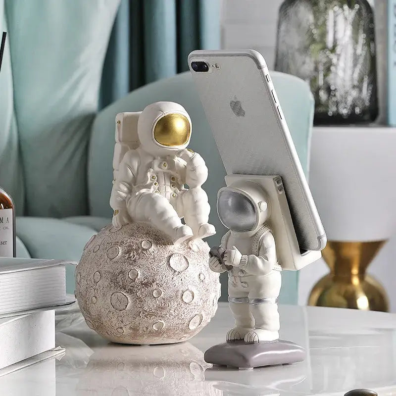 Modern white and gold astronaut phone holder figurine seated on textured moon surface for living room decorbites astronaut phone use