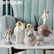Modern white and gold astronaut phone holder figurines with detailed suits displayed on a marble table for decorbites astronaut phone use