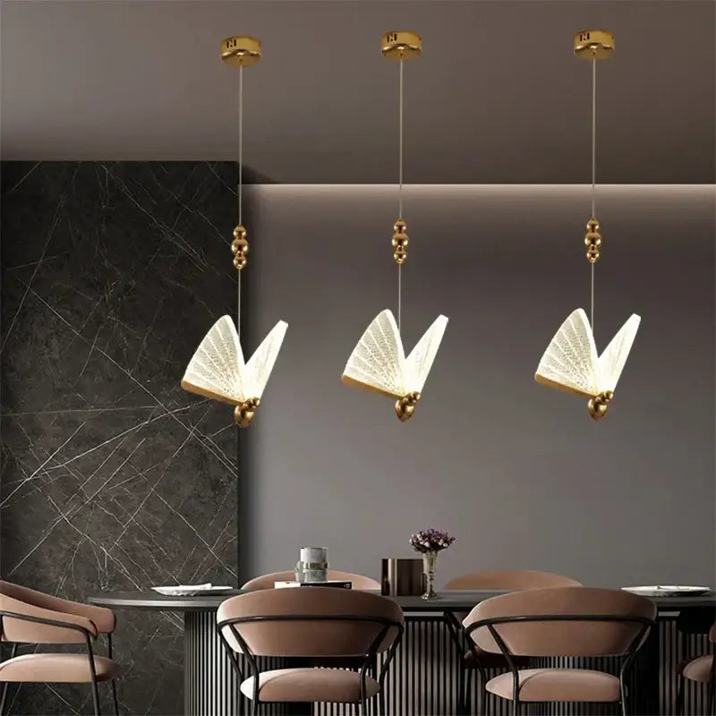 Three elegant gold-toned decorbites butterfly pendant lights with translucent illuminated wings for bedroom decor