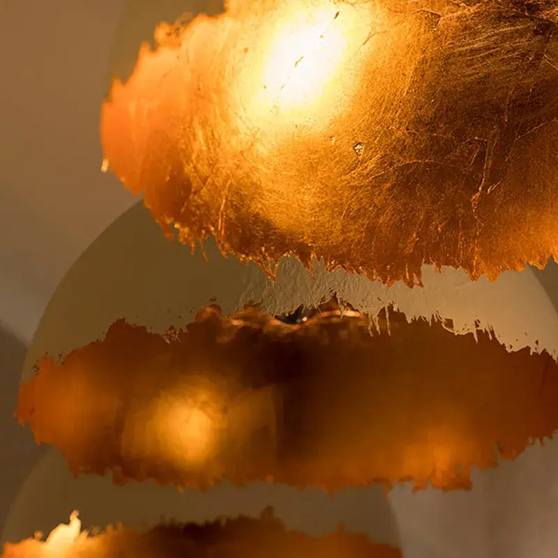 Modern white and gold eggshell acrylic resin sphere pendant light with golden textured lampshade and warm glow