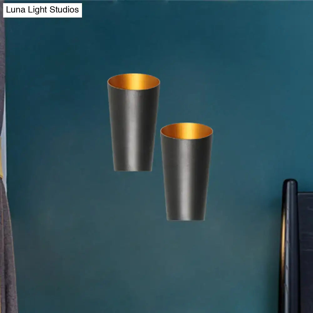 Two sleek cylindrical modern led bedside sconces with matte black exterior and warm gold interior wall light