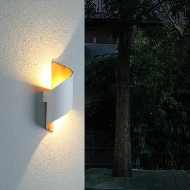 Modern white and gold outdoor wall lamp with a warm curved design and gold-toned interior spiral sconce