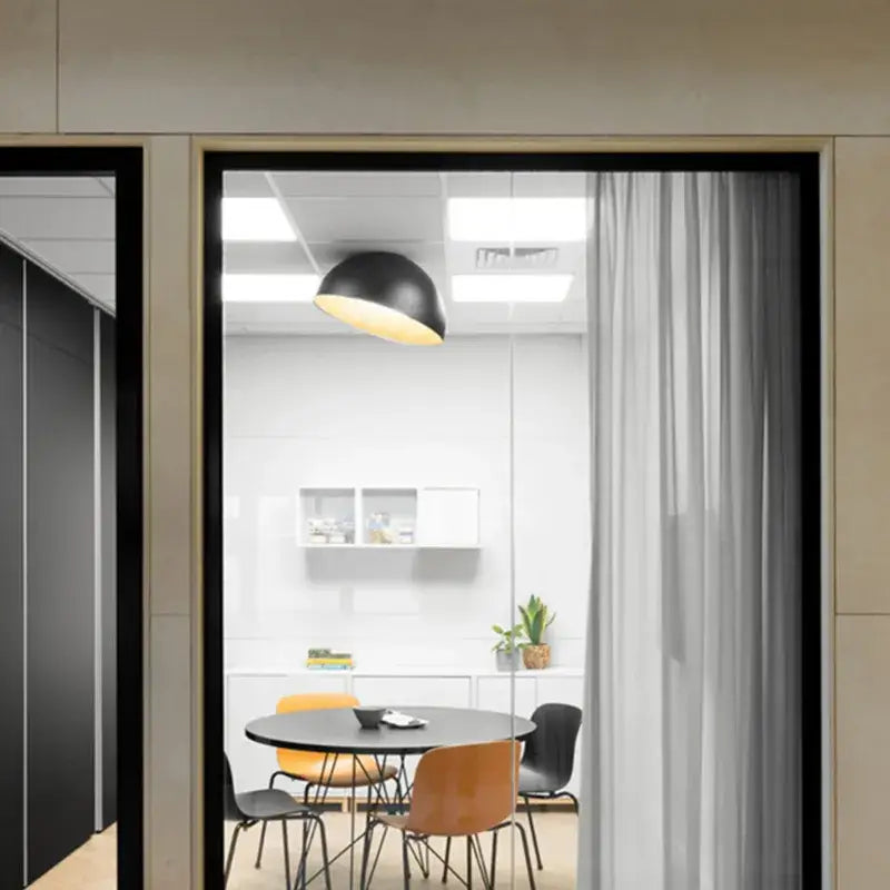 Black dome-shaped pendant ceiling light with warm yellow glow part of a modern white and wood duo ceiling light set