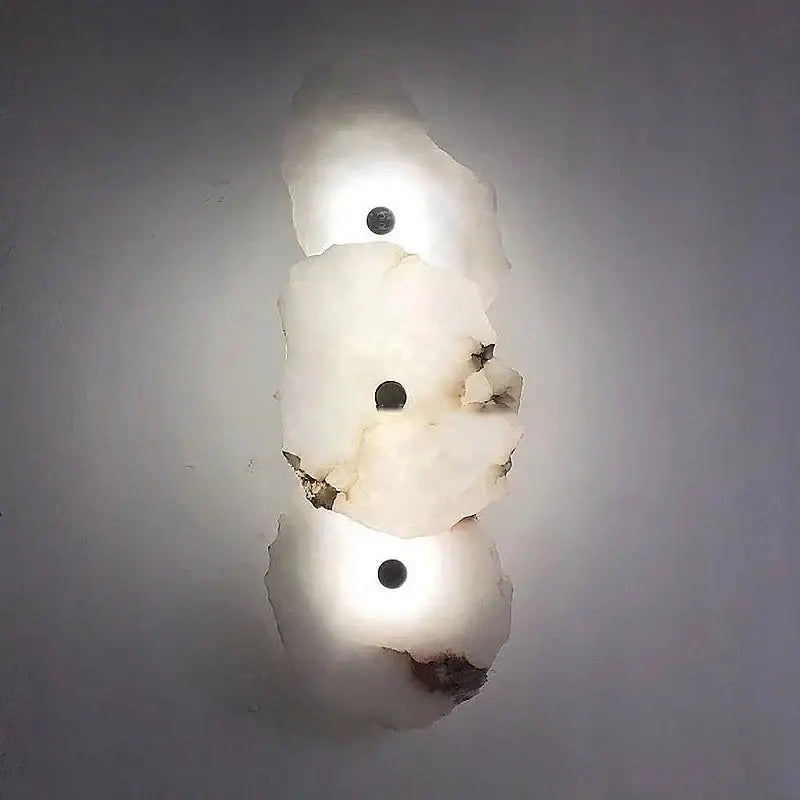 A modern wall lamp with three white frosted glass shades and black bulbs in a decorbites brass wall lamp design