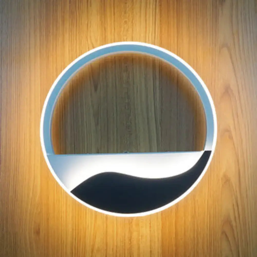 Circular wooden door with light blue metallic rim and black-and-white wave pattern beside modern acrylic wall sconce warm white light