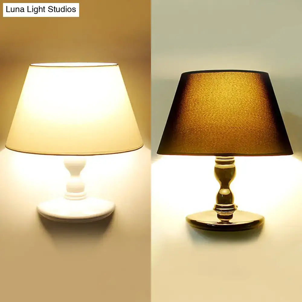 A classic table lamp with a white black cone ceramic base and a tapered fabric shade for bedroom lighting