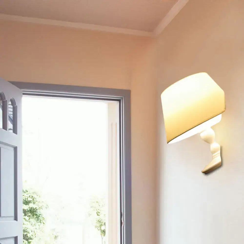 Modern white black cone ceramic wall sconce with a cream fabric lampshade and sculpted white ceramic base for bedroom use