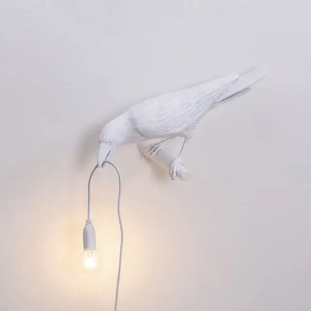 Modern white ceramic wall lamp shaped like a crow holding an exposed bulb decorbites designer bird wall light