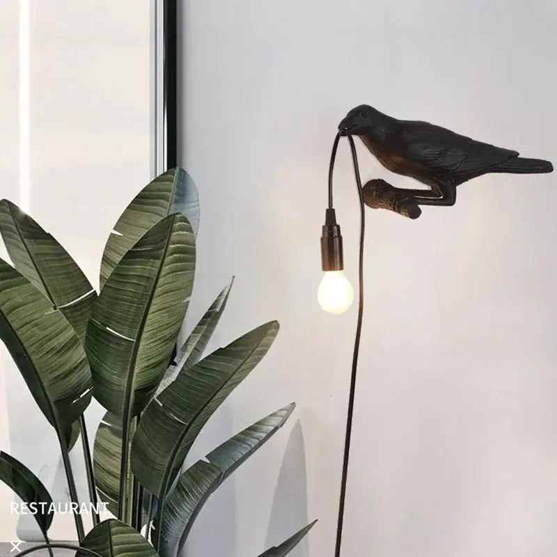 Modern white and black decorbites designer bird wall lamp featuring a black crow shape with a bulb in its beak