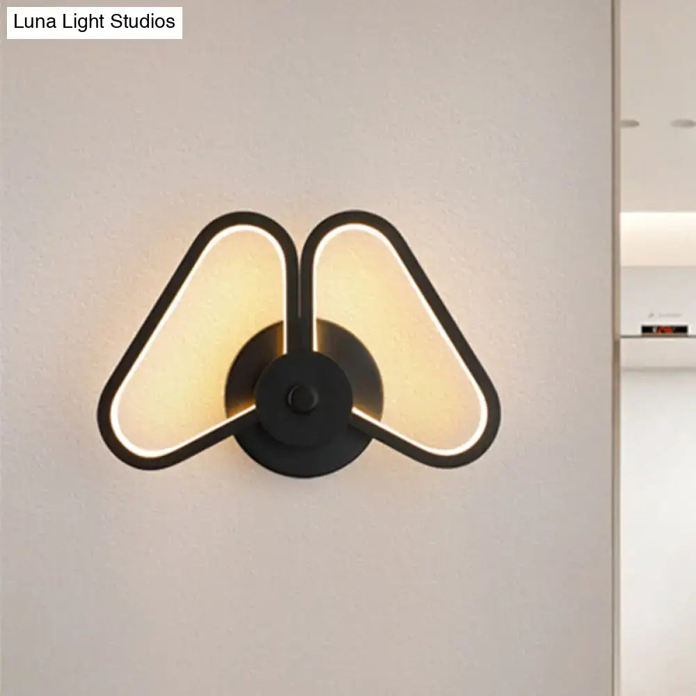 Modern white black led triangle wall sconce with black minimalist design and two warm glowing triangular light panels