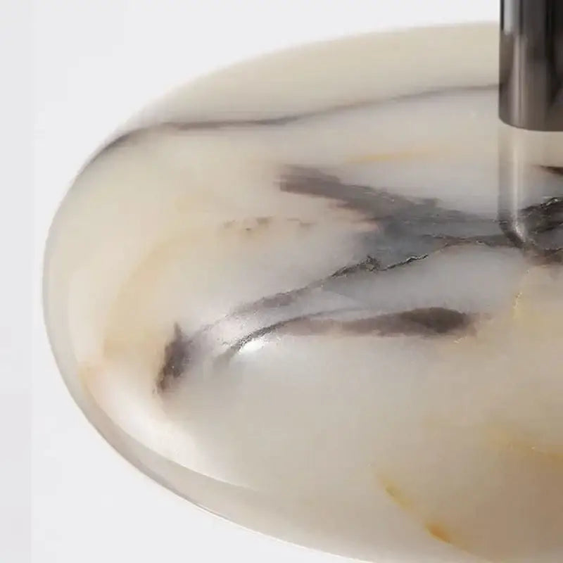 A modern white and black marble bedside pendant light featuring a sleek oval white marble sink with dark gray veining