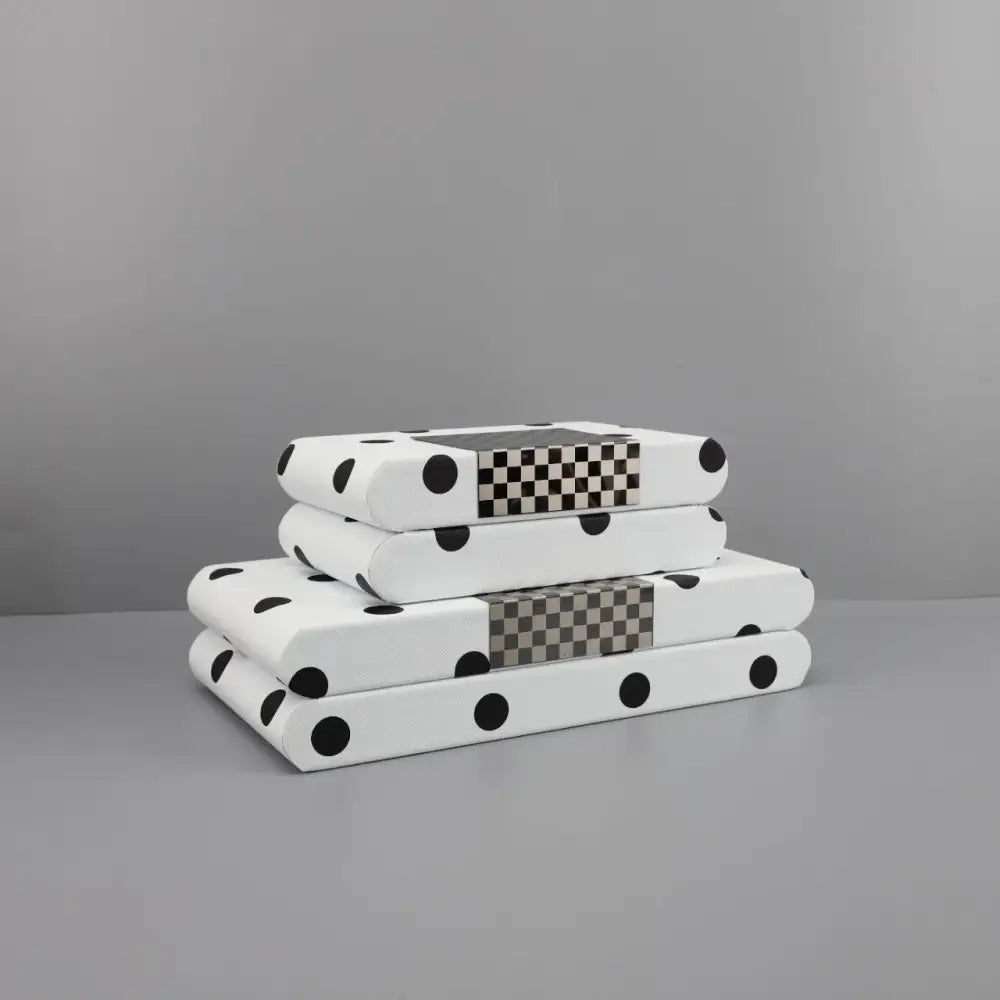 Stack of three white polka dot leather storage box books with black checkered spines for bedroom organizer use