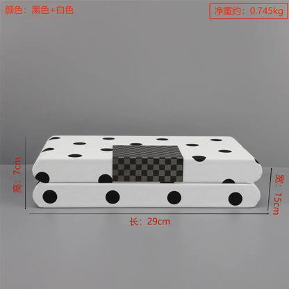 Modern white and black polka dot leather storage box with a white rectangular cushion featuring black polka dots and a checkered panel
